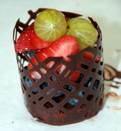 Molded chocolate lace cup around a small cake wiht berries